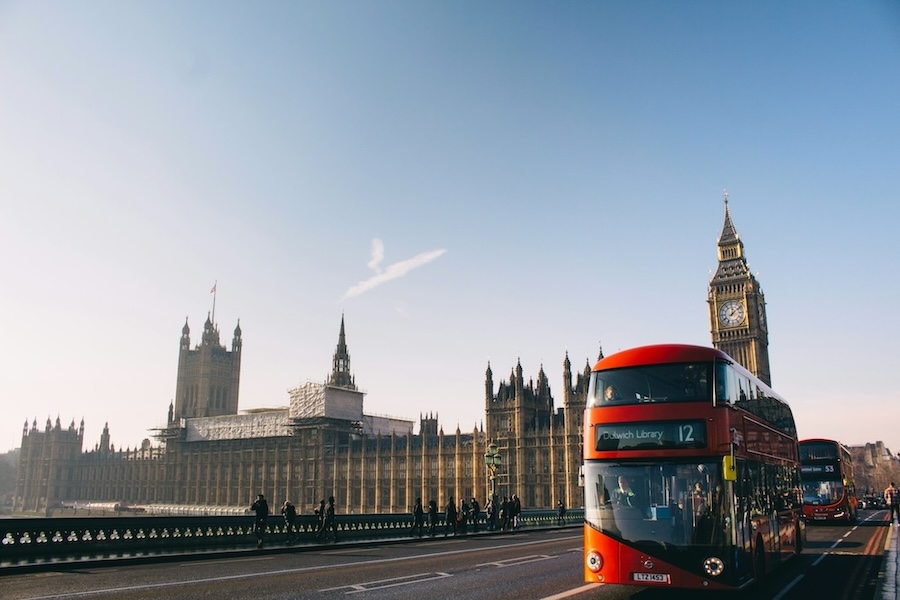 Red double decker bus driving past Big Ben and the Houses of Parliament in London