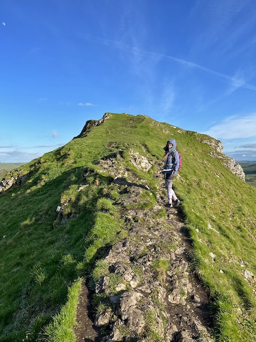 Walker on the narrow ridge path of Parkhouse Hill in the Peak District