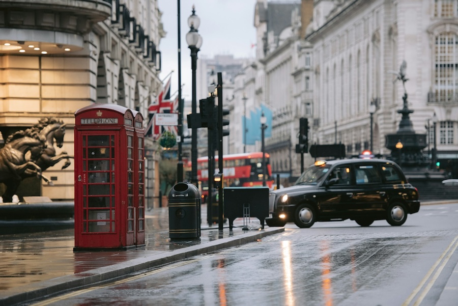 Red telephone boxes and a black taxi on a wet London street near Piccadilly Circus